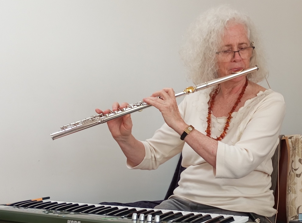 Nandin sitting at keyboard, laying the flute